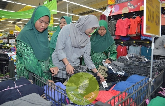 Guardian employee helping children to pick their Raya outfits