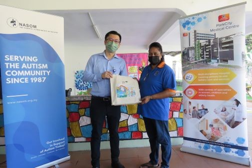 Dr Ong Kuo Ghee, Acting Chief Executive Officer, ParkCity Medical Centre (left) presents goodies to Ms Manonmaney d/o Muniandy from NASOM Titiwangsa Centre during their visit 